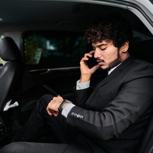 Curly-haired businessman in the backseat talking on the phone.