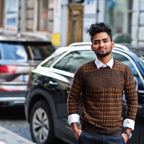 Portrait of young stylish indian man model pose in street against suv car.